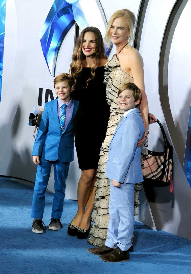 Four people posing on a blue carpet.