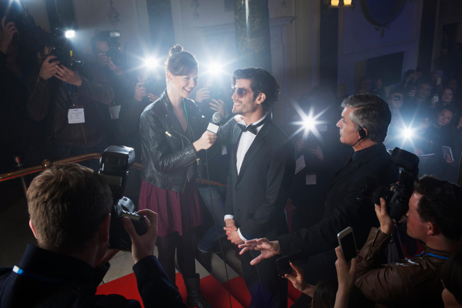 Celebrity interview on red carpet with photographers.