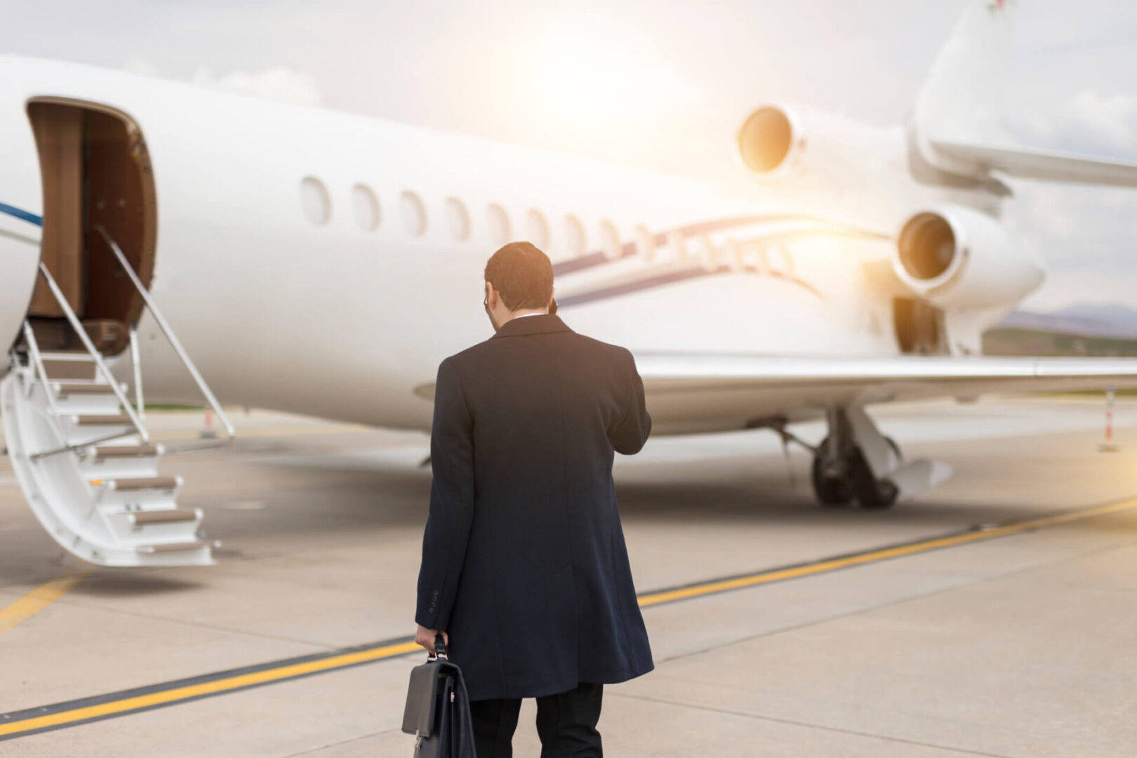 Man approaching private jet with briefcase.
